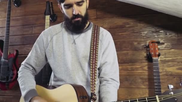 Bonito barbudo homem tocando o acústico guitarra lento movimento — Vídeo de Stock