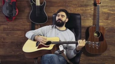 akustik gitar yavaş oynayan yakışıklı sakallı adam