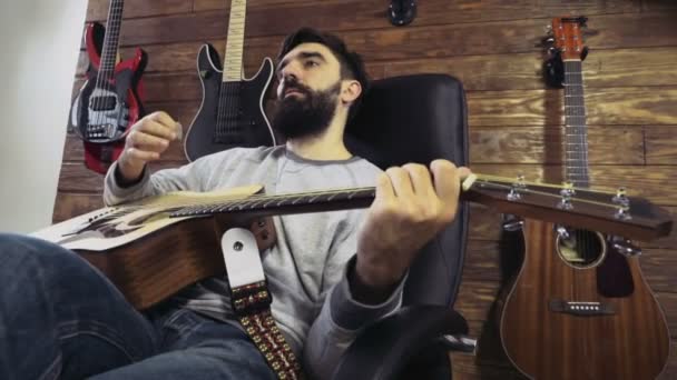 Knappe bebaarde man spelen de akoestische gitaar Slowmotion — Stockvideo