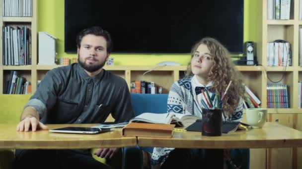 Casal de alunos sentados na sala de aula e assistindo à câmera — Vídeo de Stock