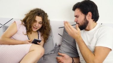 Yatak yavaş çekimde bir akıllı telefon kullanan kadın için konuşan adam