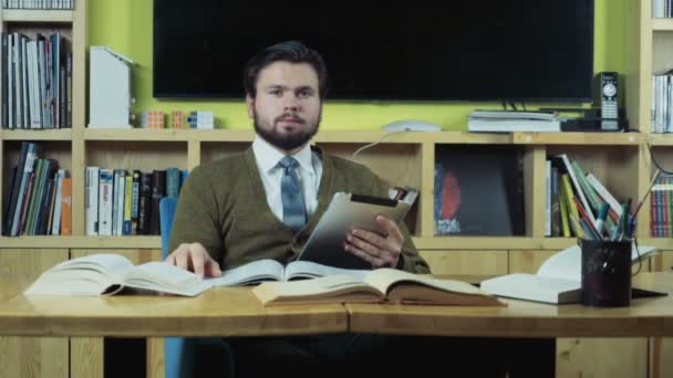 Estudiante masculino mirando a una cámara mientras está sentado en la sala de clase — Vídeo de stock