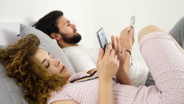 Homme et femme au lit en utilisant des gadgets au ralenti — Video