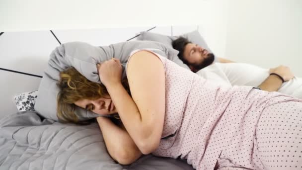 Vrouw haar hoofd onder het hoofdkussen verbergen tijdens het slapen met een man slow motion — Stockvideo