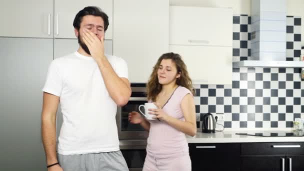 Esposa trayendo una taza de café a su marido somnoliento en la cocina cámara lenta — Vídeo de stock