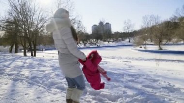 Anne ve kızı parkta bir güneşli kış gününde eğleniyor