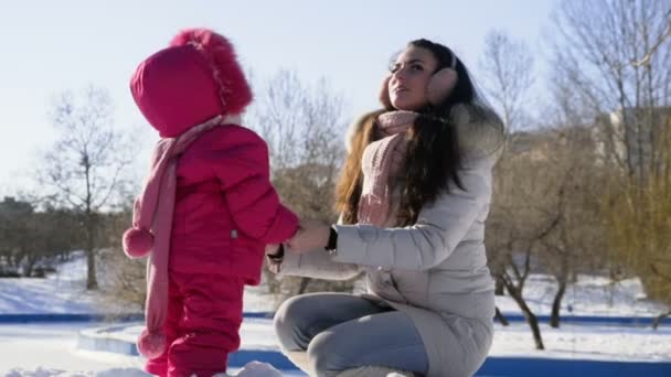 Мать и дочь гуляют в парке в солнечный зимний день — стоковое видео