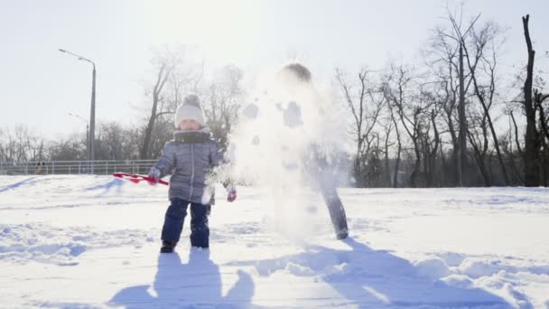 Мати і дочка грають у снігу в парку повільний рух — стокове відео