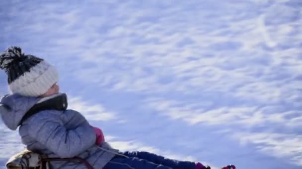 Kind auf Schlitten fährt in Zeitlupe den Berg hinunter — Stockvideo