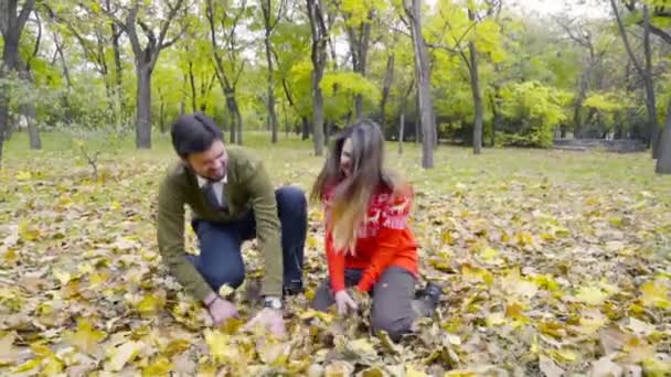 Pareja joven vomitando las hojas caídas en el parque cámara lenta — Vídeos de Stock