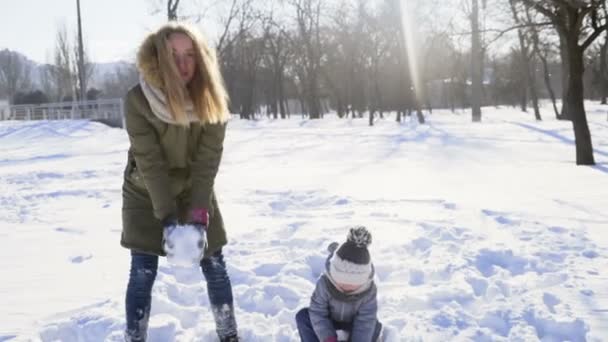 Мать и дочь выбрасывают снег в парке замедленной съемки — стоковое видео