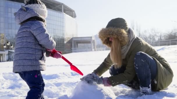 Madre e hija construyendo algo de nieve cámara lenta — Vídeos de Stock