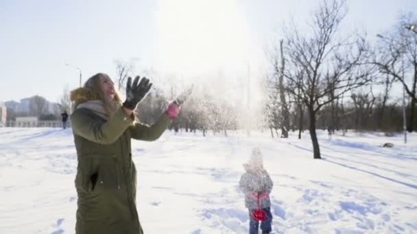 Μητέρα και κόρη παίζει με το χιόνι σε αργή κίνηση το πάρκο — Αρχείο Βίντεο