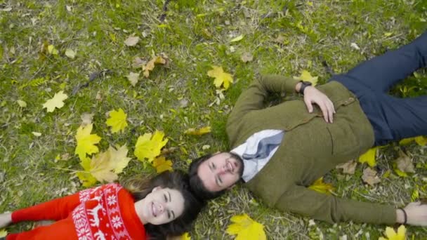 Vue de dessus du jeune couple étendu sur le sol dans le parc d'automne — Video