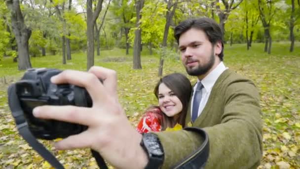 Pareja joven haciendo selfie con una cámara en el parque de otoño — Vídeo de stock