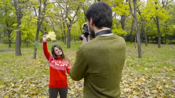 Mannelijke nemen van foto's van een jonge vrouw in het najaar park Slowmotion — Stockvideo