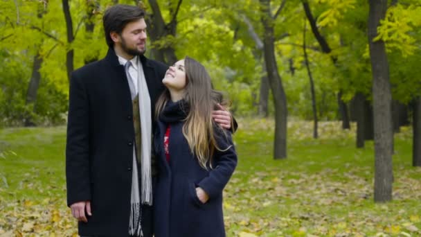 Портрет молодой счастливой пары в пальто в осеннем парке — стоковое видео