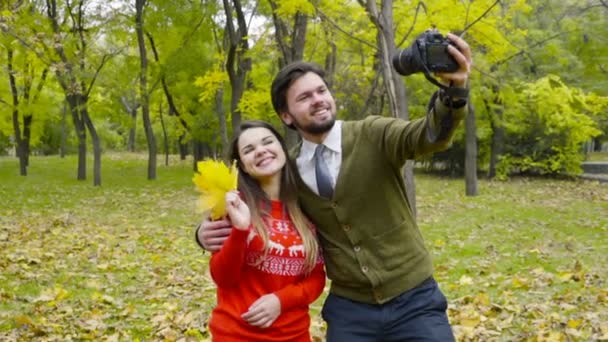Jovem casal fazendo selfie com uma câmera no parque de outono — Vídeo de Stock