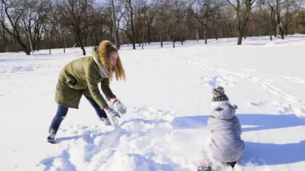 Mor och dotter spelar i snön i parken slow motion — Stockvideo