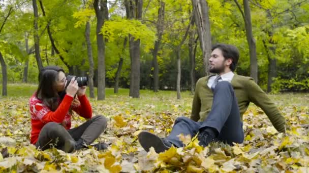 Jovem do sexo feminino tirar fotos de um homem no parque de outono câmera lenta — Vídeo de Stock