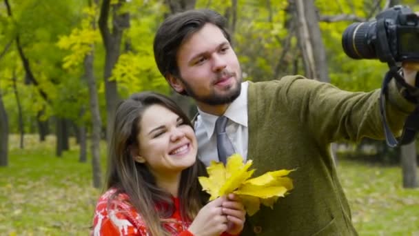 Pareja joven haciendo selfie con una cámara en el parque de otoño — Vídeos de Stock