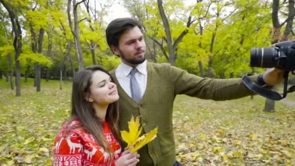 Pareja joven haciendo selfie con una cámara en el parque de otoño — Vídeo de stock