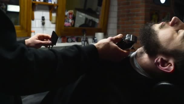 Парикмахер бреет бороду клиента клиппером замедленным движением — стоковое видео