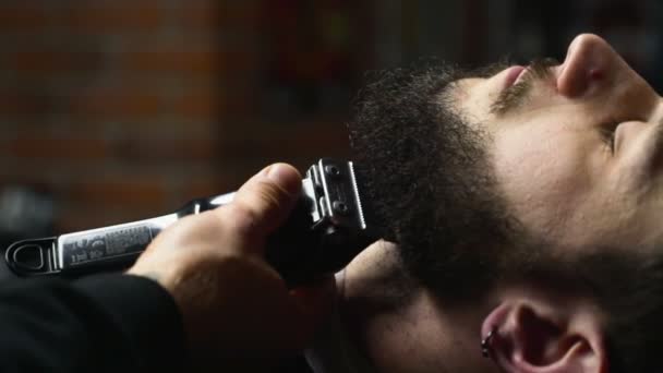 Barbeiro barba a barba do cliente com clipper câmera lenta de perto — Vídeo de Stock