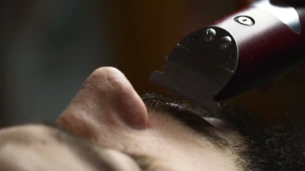 Peluquero afeita la barba del cliente con trimmer cámara lenta de cerca — Vídeos de Stock