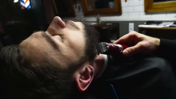 Peluquero afeita la barba del cliente con trimmer cámara lenta — Vídeos de Stock