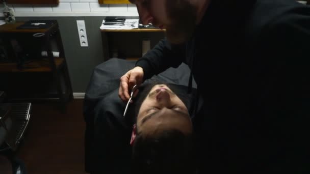 Peluquero corta el pelo de la barba del cliente con tijeras de cámara lenta — Vídeo de stock