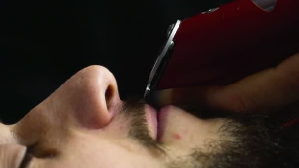Peluquero afeita la barba del cliente con trimmer cámara lenta de cerca — Vídeos de Stock