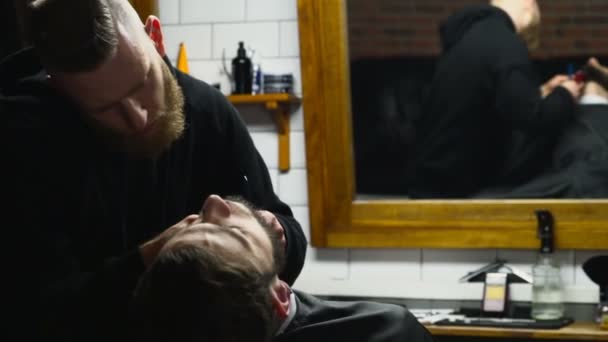 Barber holí vousy klienta s sekačky Zpomalený pohyb — Stock video