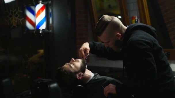 Barber coupe les cheveux de barbe du client avec des ciseaux au ralenti — Video