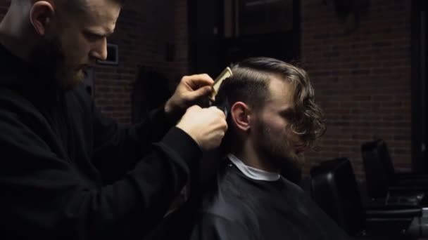 Парикмахер стрижет волосы клиента клиппером замедленным движением — стоковое видео