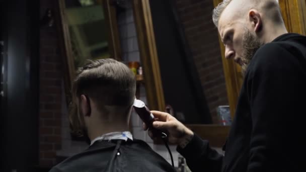 Barber cuts the hair of the client with trimmer slow motion — Stock Video