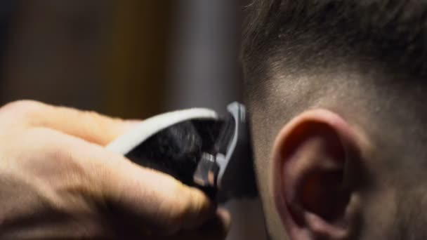 Peluquero corta el cabello del cliente con el clipper cámara lenta de cerca — Vídeos de Stock