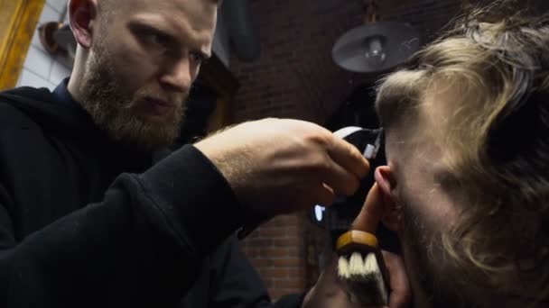 Перукарня ріже волосся клієнта з clipper повільний рух — стокове відео