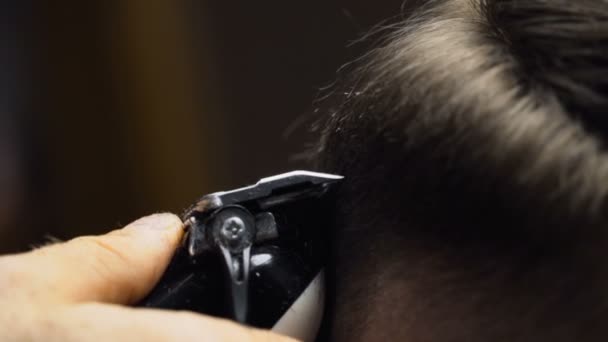 Kapper bezuinigingen de haren van de klant met clipper slowmotion close-up — Stockvideo