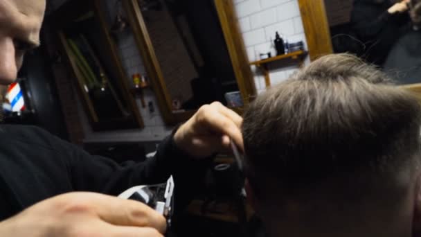 Barber coupe les cheveux du client avec tondeuse au ralenti gros plan — Video