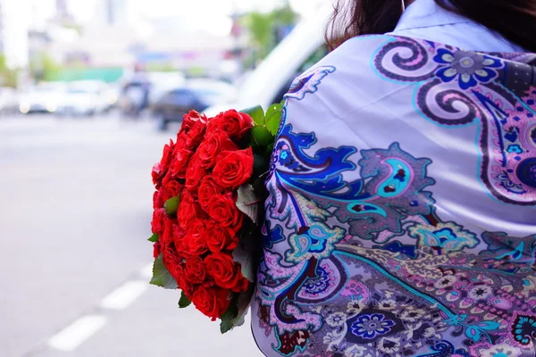 Schöne Mädchen mit langen Haaren mit einem großen Strauß Rosen — Stockfoto