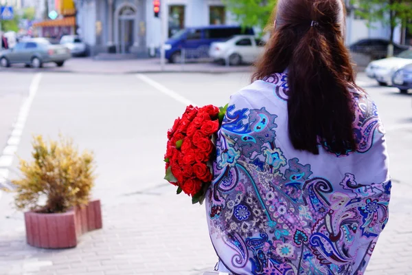 Schöne Mädchen mit langen Haaren mit einem großen Strauß Rosen — Stockfoto