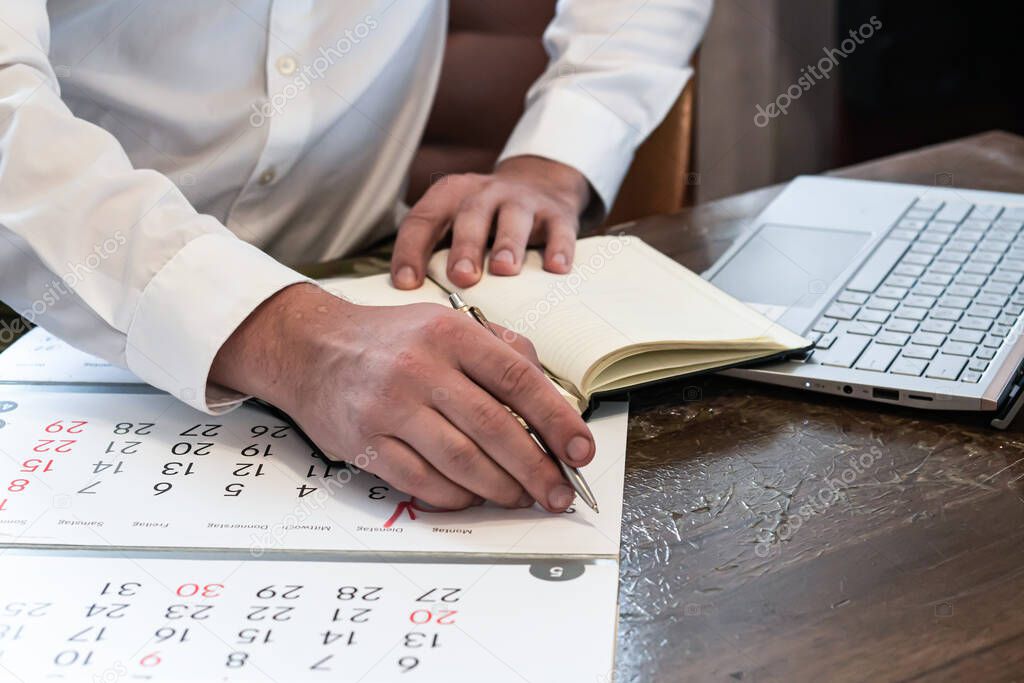 guy's hands, on the background of a laptop and a calendar. Work from home