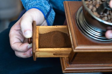 El yapımı öğütücü kahve çekirdeklerini öğütüyor. Kavrulmuş Arap taneleri yığını..