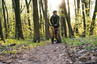 Hırslı bir manyetik bisikletçi orman yolunda tek başına yürüyor, bisikleti ve iki elini tutuyor, doğanın tadını çıkarıyor. Spor konsepti.