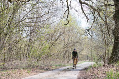 Adam ormanda, orman yollarında at sürüyor.