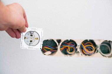 Alçıtaşı duvarına soket takan elektrikçinin elleri