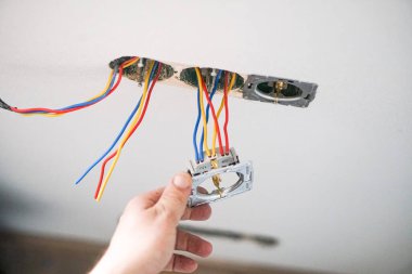 Alçıtaşı duvarına soket takan elektrikçinin elleri