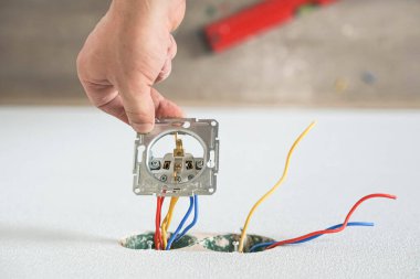 Alçıtaşı duvarına soket takan elektrikçinin elleri