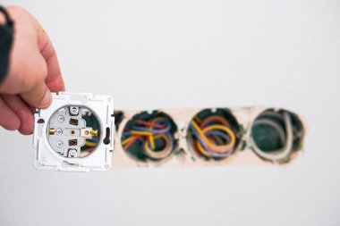 Alçıtaşı duvarına soket takan elektrikçinin elleri